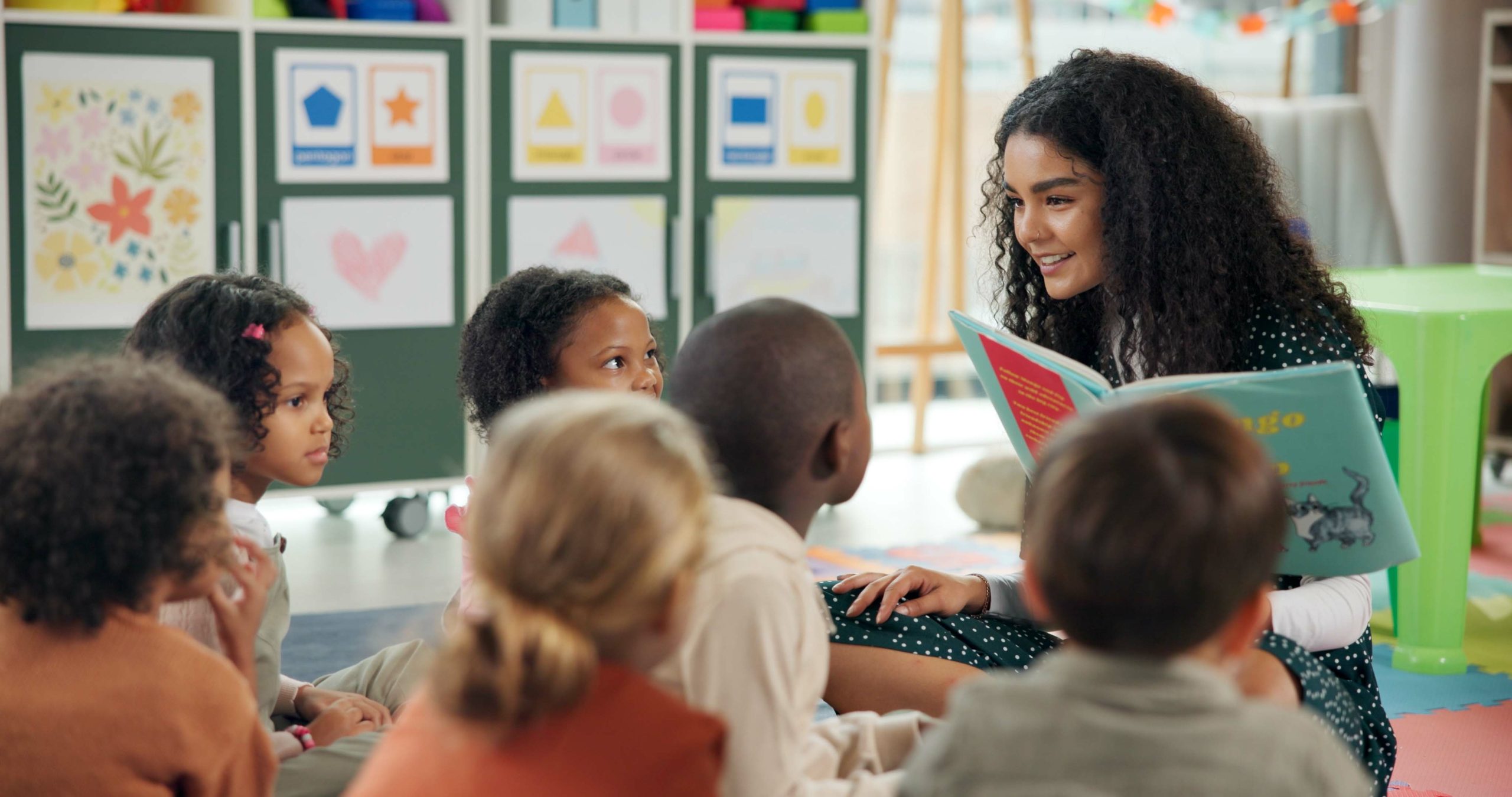 Reading, students and teacher with children in classroom for education, books and creative